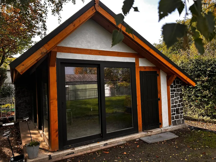 Het nieuwe atelier: puntgevel met houten balken, witte pleister en grote zwarte puien