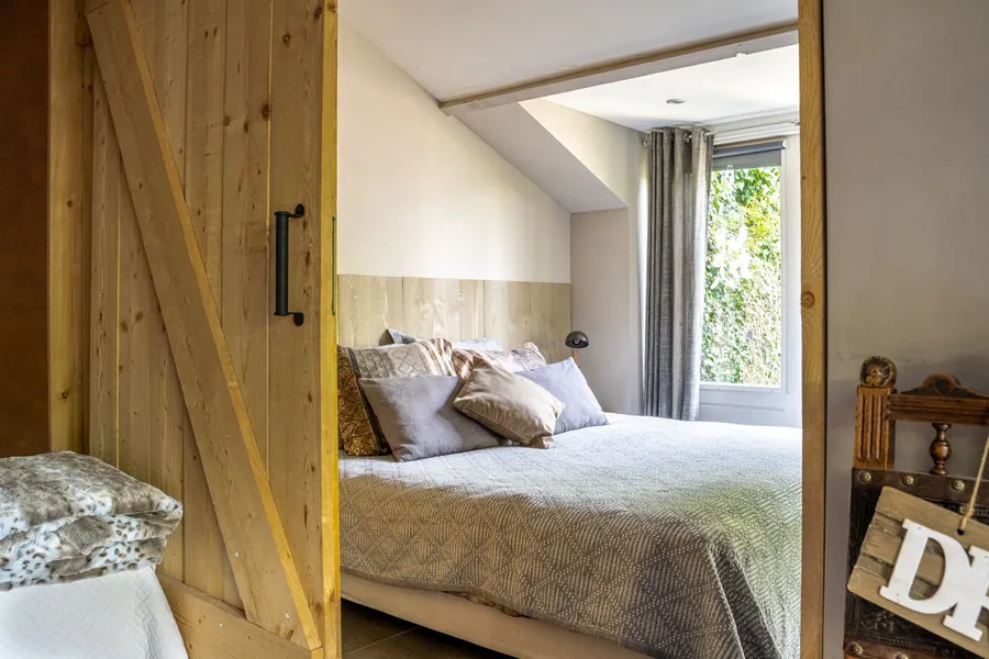Tweepersoonsbed in Dream, zichtbaar door de houten schuifdeur