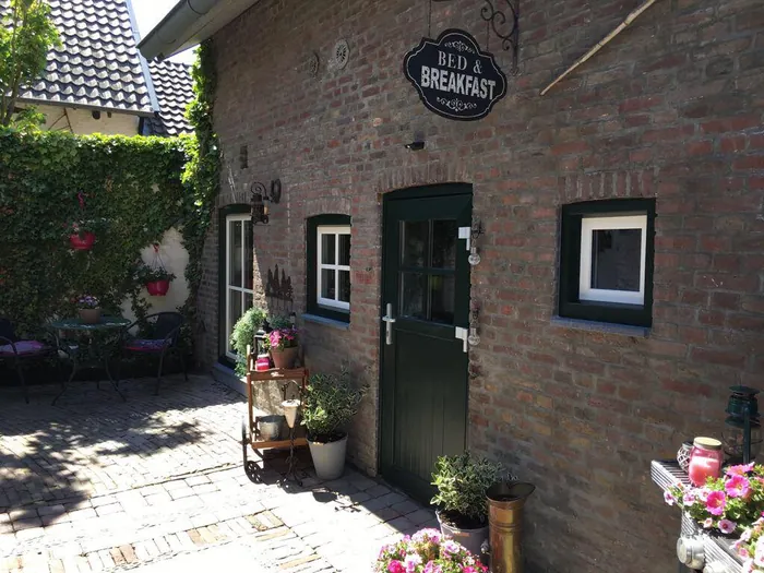 Bakstenen gevel met groene deur en bord Bed & Breakfast