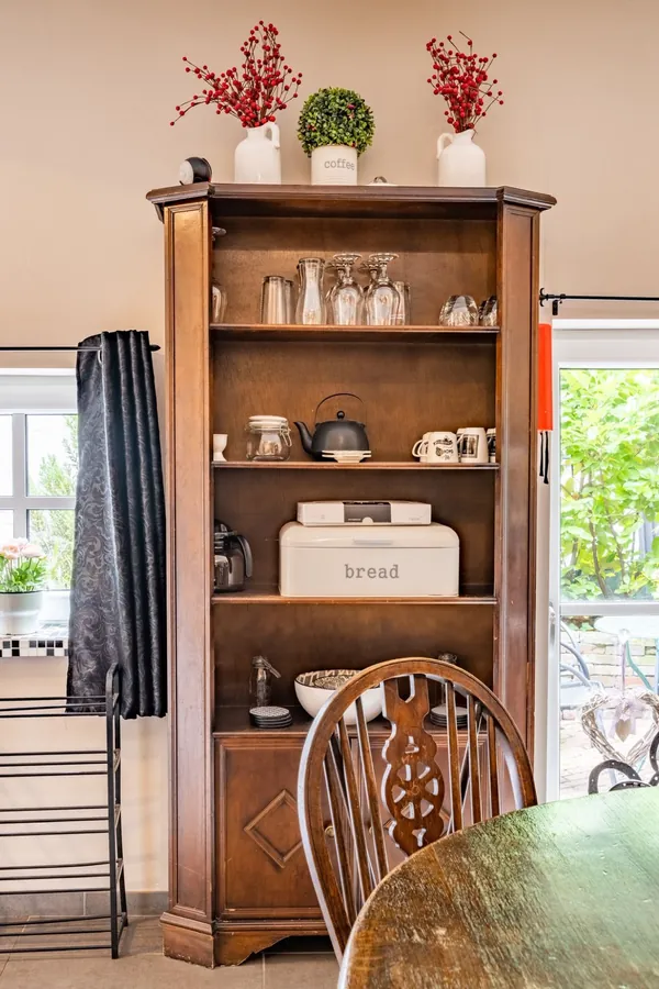 Houten servieskast met glazen, theepot en broodtrommel