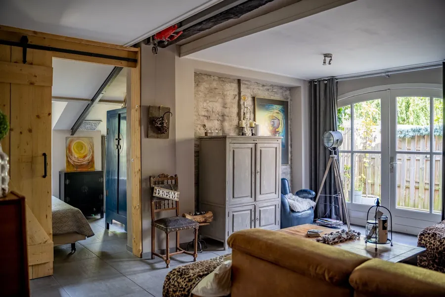 Woonkamer van Dream met grijze kast, schilderijen en gebogen tuindeuren
