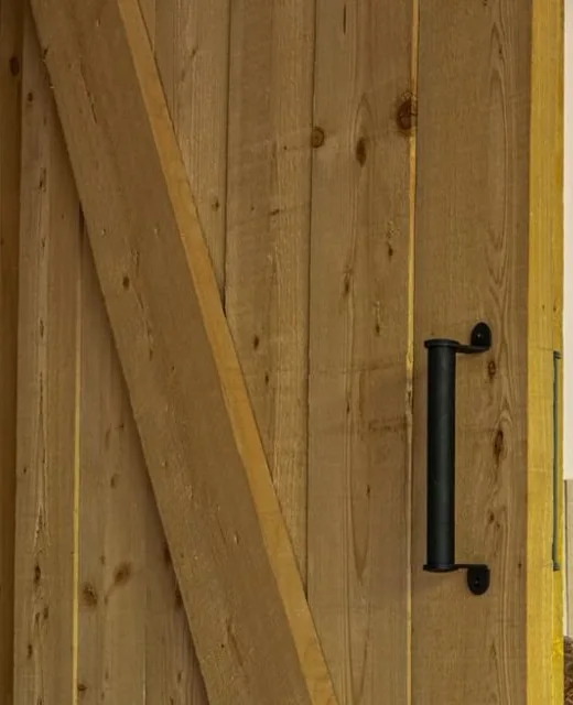 Schuifdeur van ruw hout met zwarte greep