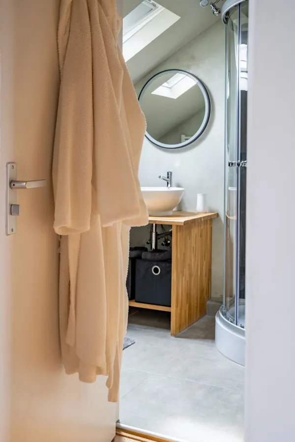 Badkamer met ronde spiegel, waskom op houten meubel en douche