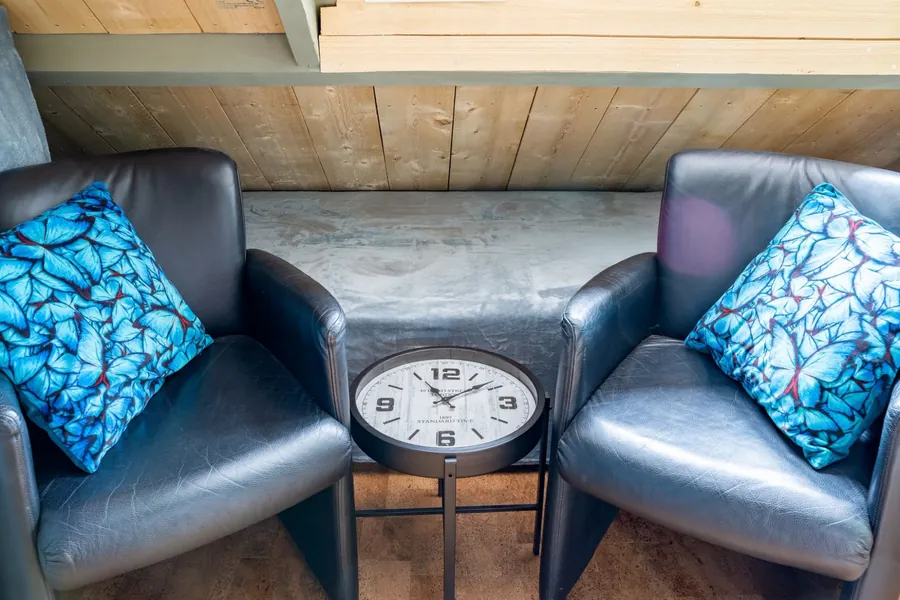 Twee leren fauteuils met blauwe vlinderkussens en een klokje als bijzettafel
