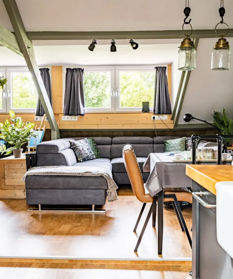 Woonkamer van de ArtStudio met hoekbank, eettafel en ramen met uitzicht op het groen