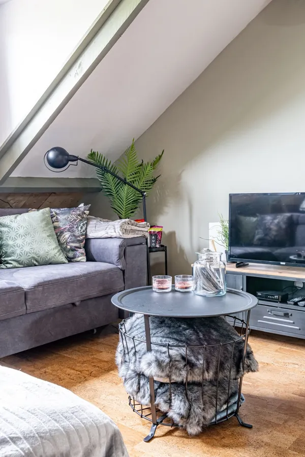 Bank, salontafel en tv onder het schuine dak